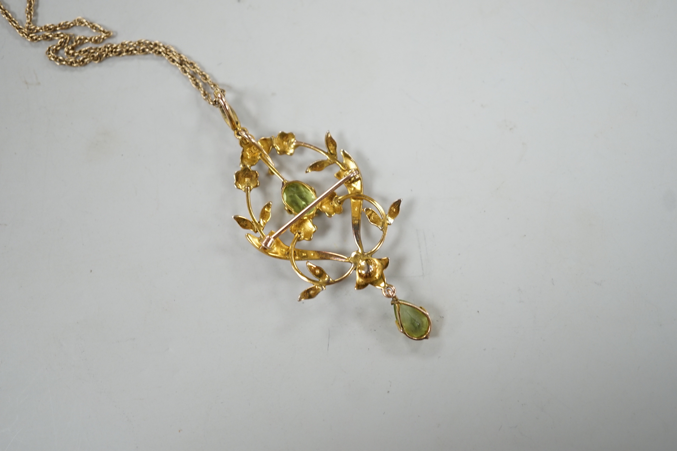 An Edwardian 9ct, peridot and seed pearl set drop pendant brooch, 57mm, on a later 375 rope twist chain, 44cm gross weight 6.7 grams.